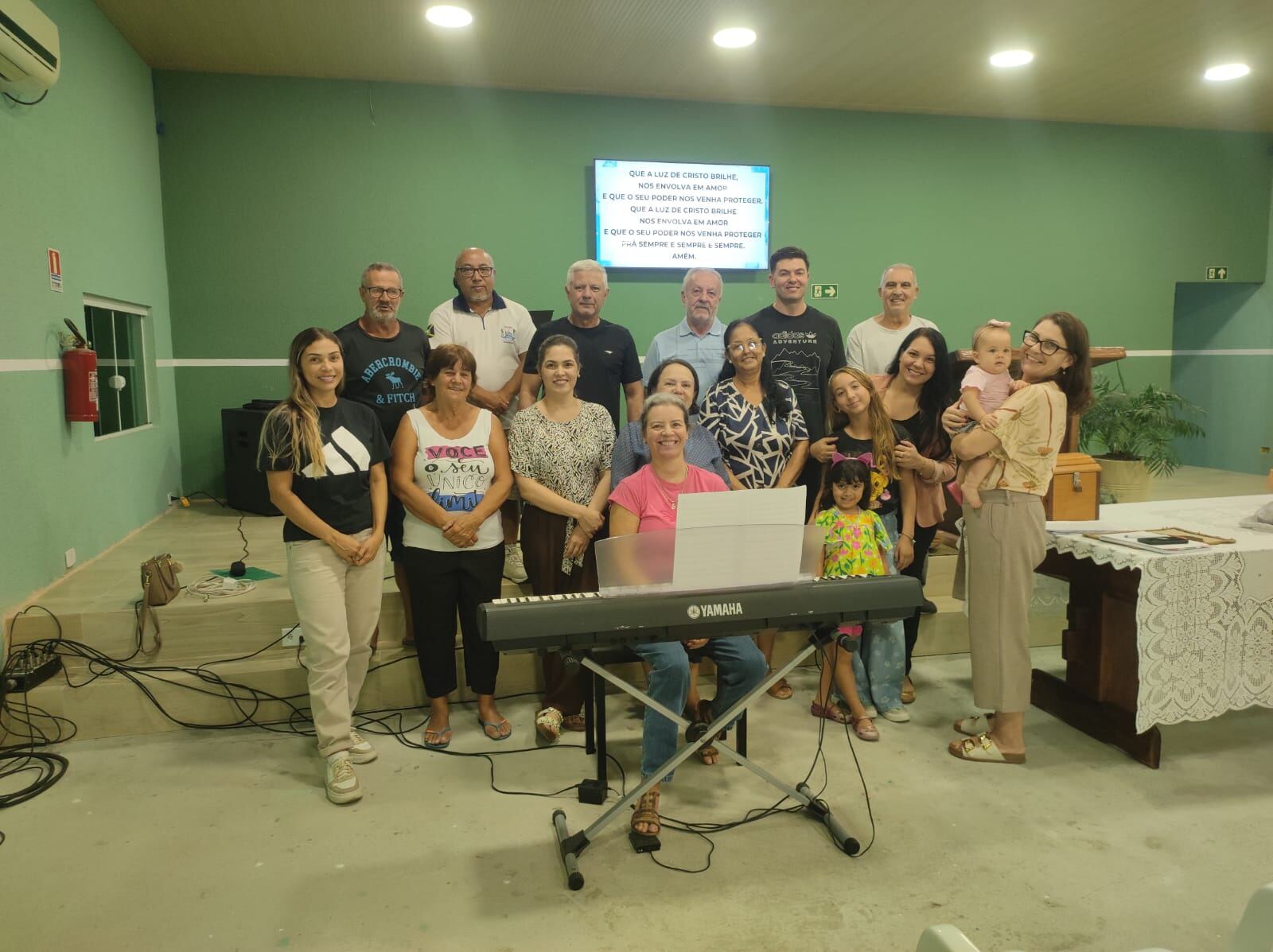 Coral da IPB Guaratuba reunido ao redor do teclado com a musicista Simone após ensaio