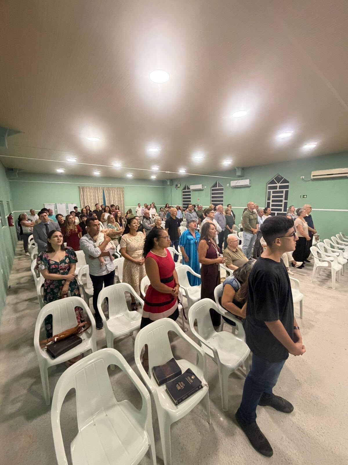 Congregação em pé entoando hinos de gratidão