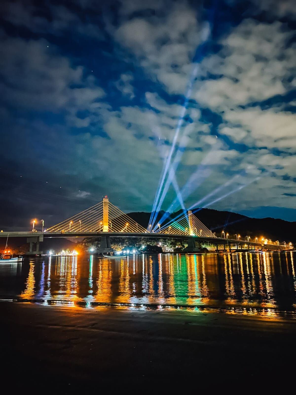 Ponte de Guaratuba iluminada à noite com show de luzes sobre a baía
