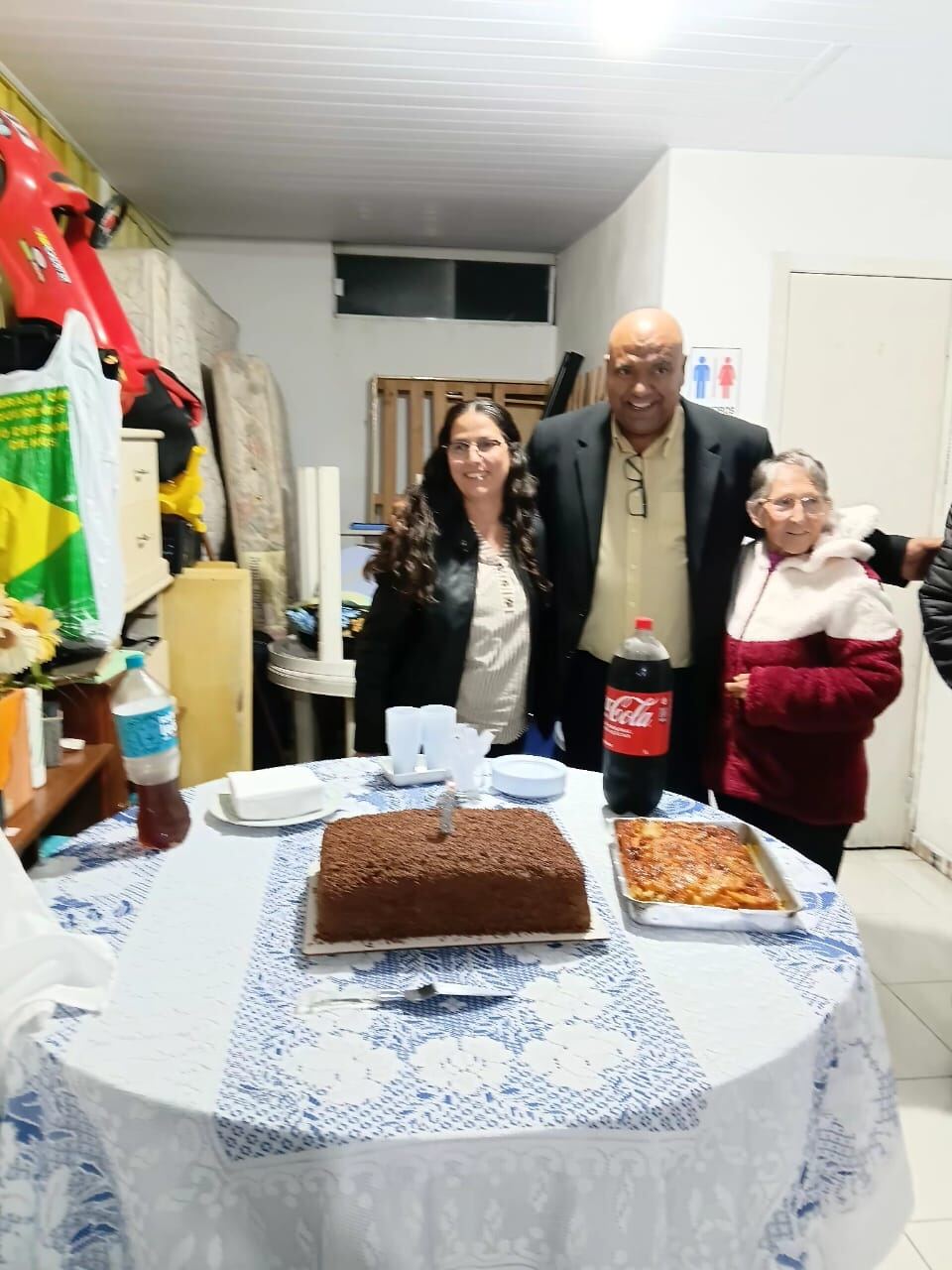 Aniversariante posando com familiares ao lado do bolo