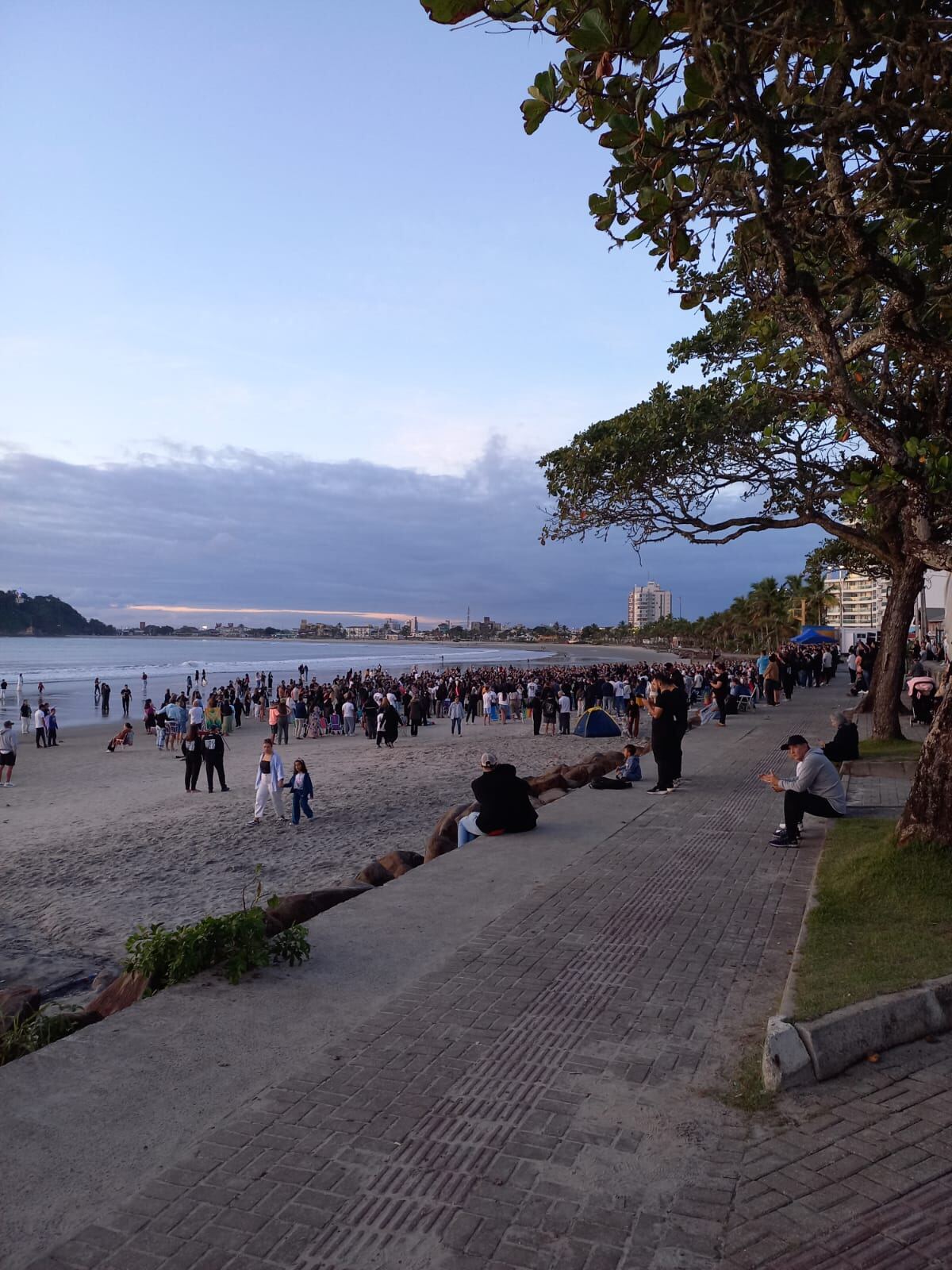 Panorama da praia de Guaratuba tomada por pessoas reunidas em oração